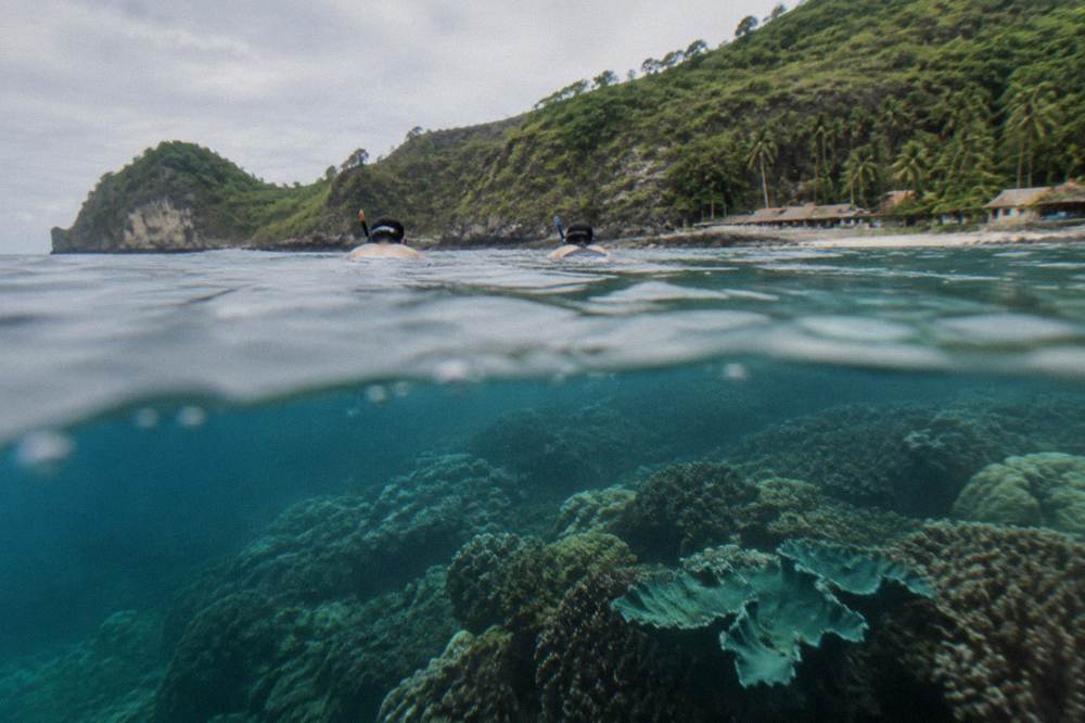 Snorkelers in calm water above a coral reef near Nusa Penida