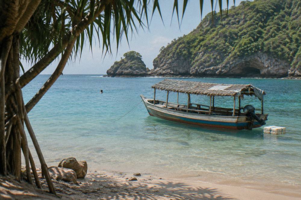 A wooden snorkeling boat anchored over clear shallow water near Nusa Penida