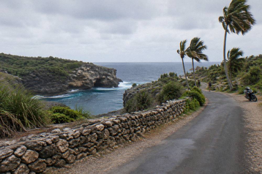 A coastal road winding along green cliffs above the sea on Nusa Penida
