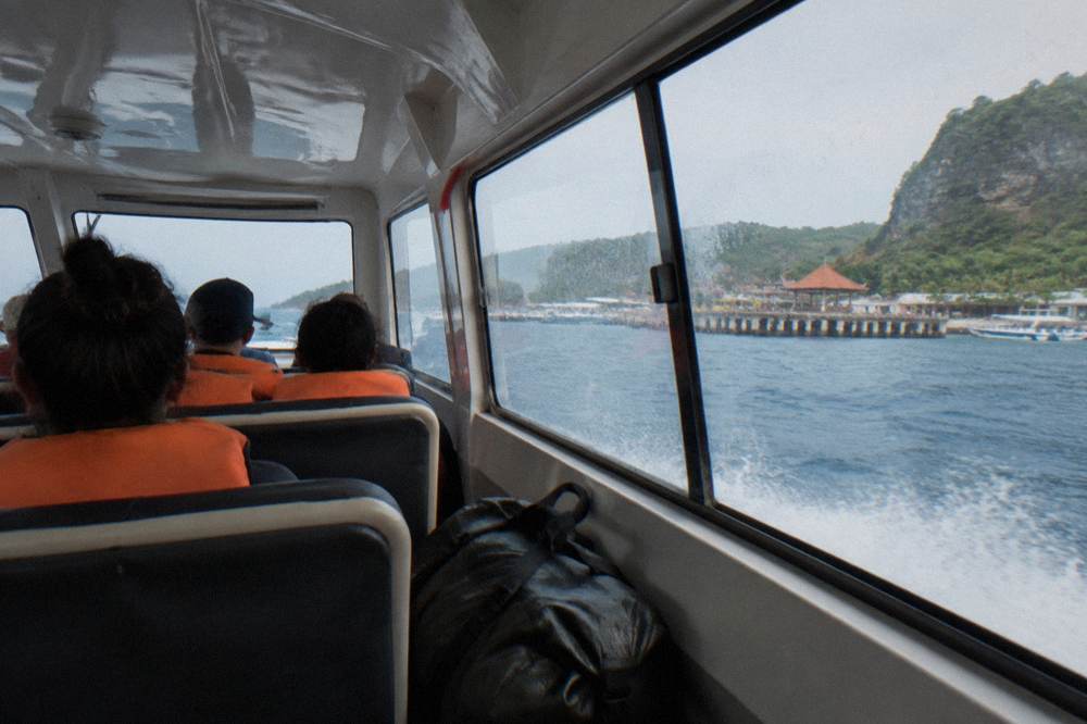 Passengers in life jackets seated inside a fast boat during the crossing to Nusa Penida