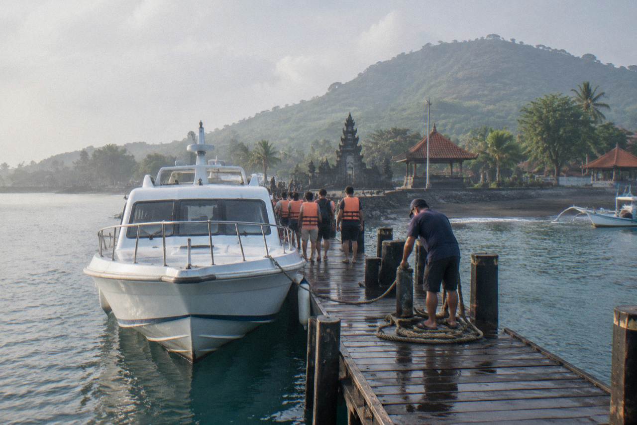 A fast boat moored at a Sanur jetty with passengers boarding for the crossing to Nusa Penida