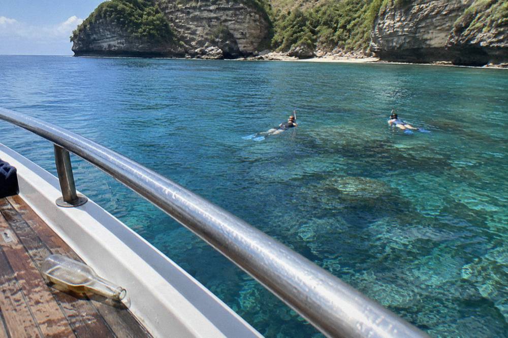 Snorkellers floating above a coral reef in clear blue water off Nusa Penida