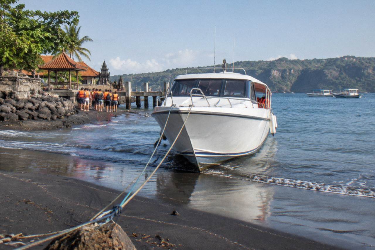 A fast boat moored at a Bali harbour with passengers boarding in the morning light
