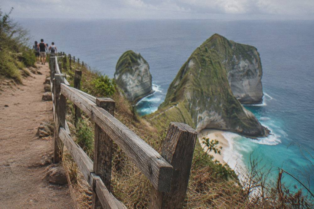 Steep cliff edge above the ocean at Kelingking Beach viewpoint with a wooden safety railing