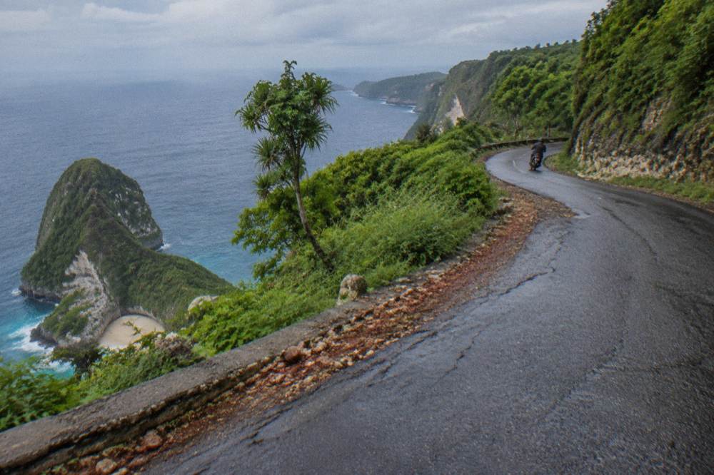 Narrow coastal road on Nusa Penida curving along a green cliffside
