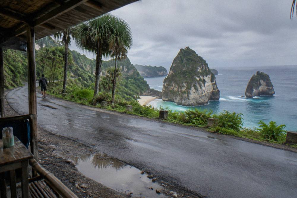 A narrow coastal road on Nusa Penida curving along green cliffs above the sea