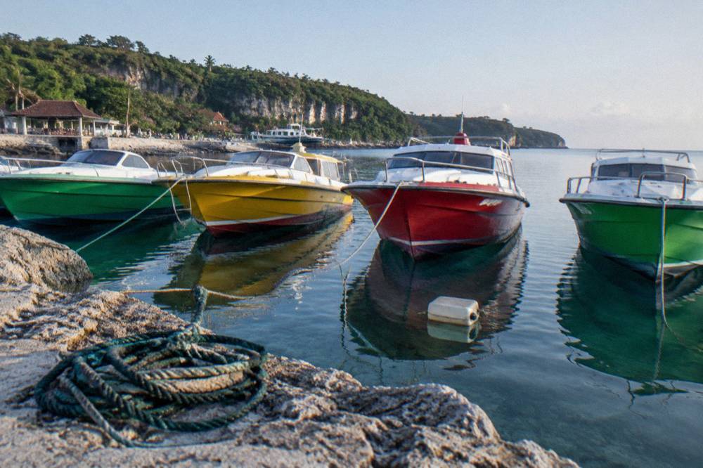 A line of colourful fast boats moored at a harbour with calm water in the morning light