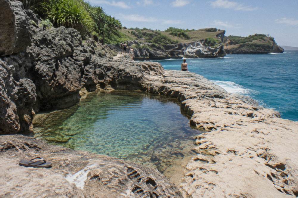 A wide viewpoint over turquoise water and limestone formations at a Nusa Penida bay in dry season light
