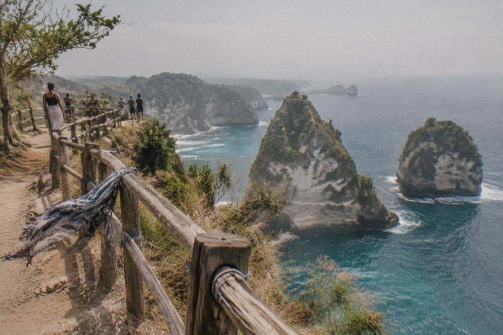Visitors gathered along a cliff edge viewpoint above the sea on Nusa Penida