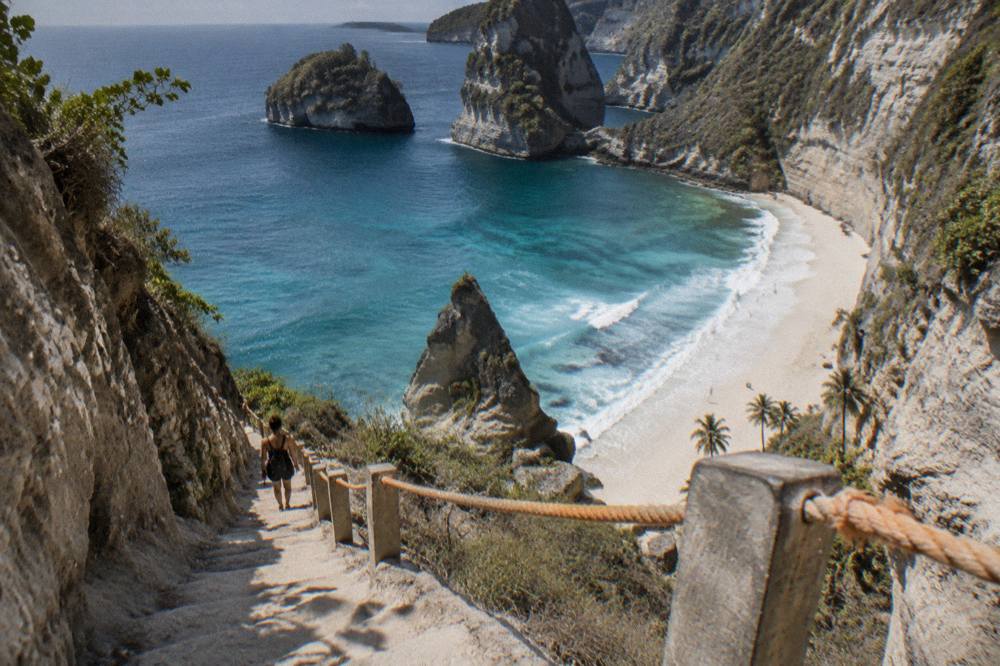 A white sand cove below tall limestone cliffs seen from a clifftop viewpoint
