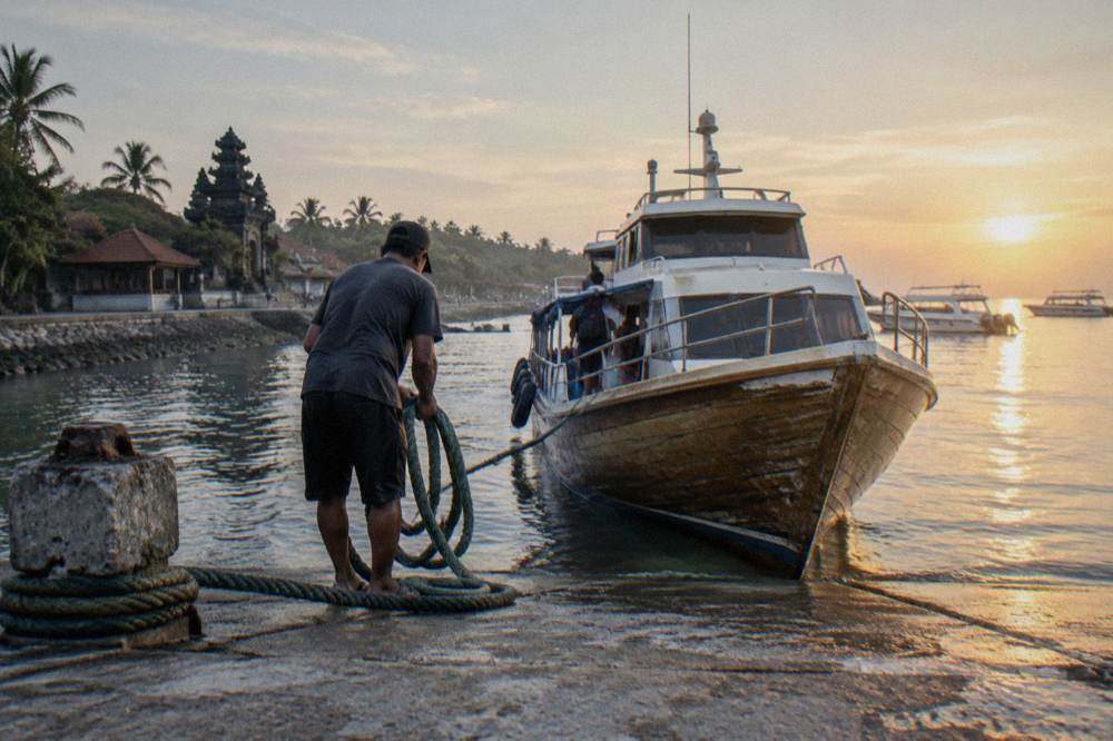A wooden fast boat moored at a beach departure point in early morning light