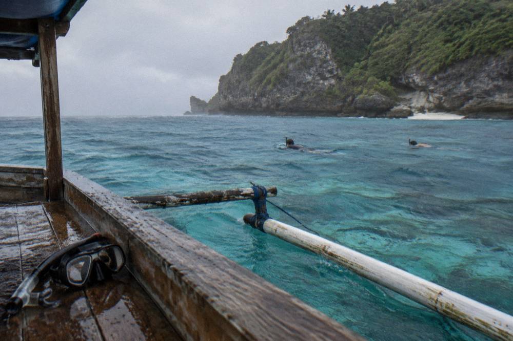 Turquoise water over a coral reef with snorkelers floating at a distance