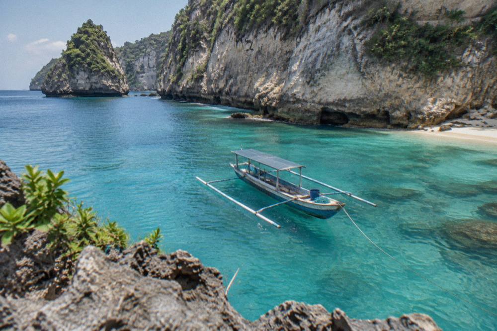 A snorkeling boat anchored near limestone cliffs above clear water