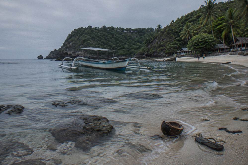 A sheltered bay with clear water, coral heads and a small boat moored near the beach