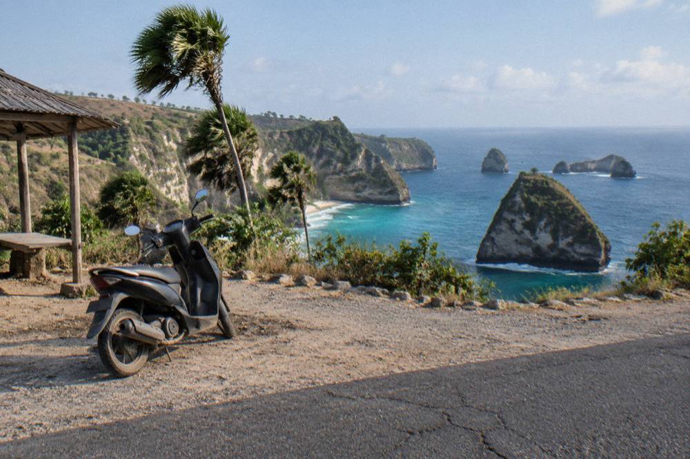 Cliffside road winding above a turquoise bay with a viewpoint pull-in