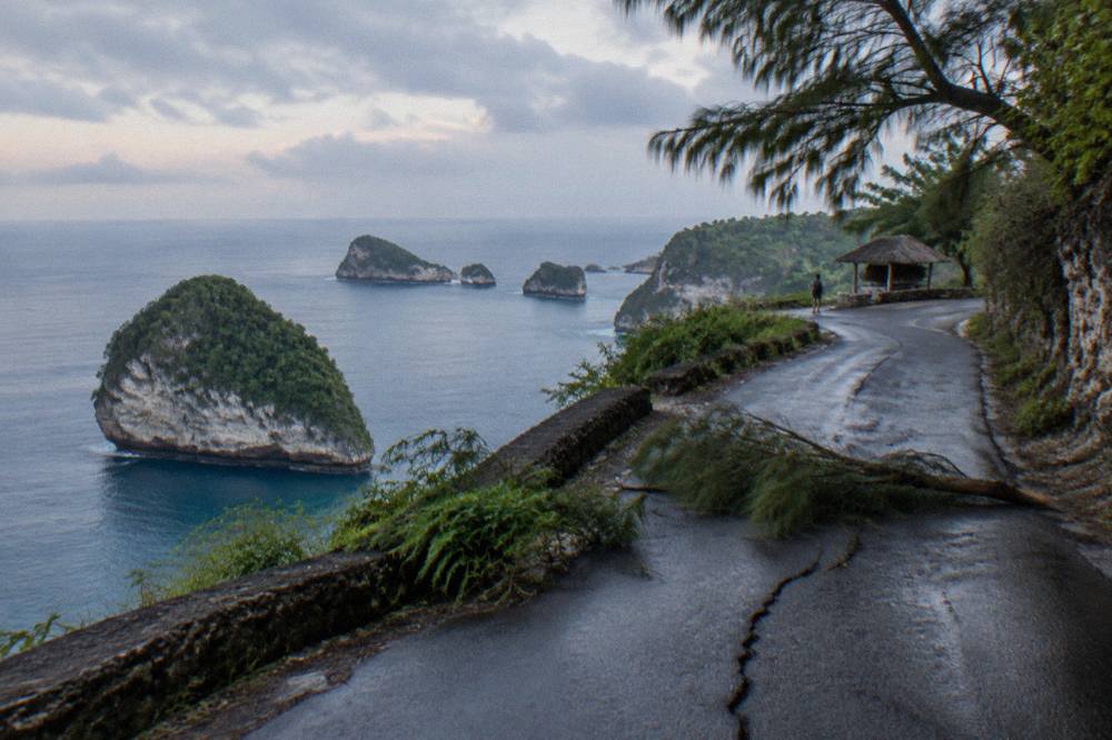 A coastal road curving along clifftops above a calm blue sea