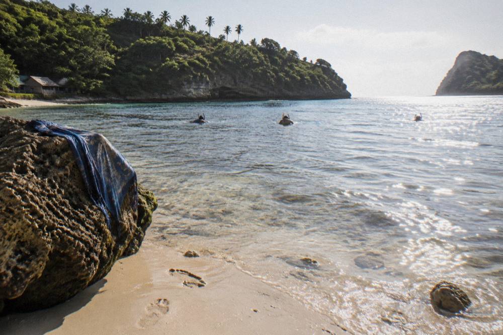 Snorkelers floating over a shallow coral reef in calm clear water