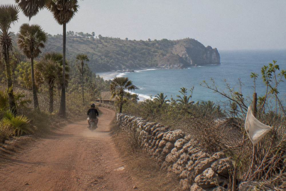 A coastal road on Nusa Penida winding above rocky cliffs toward a bay