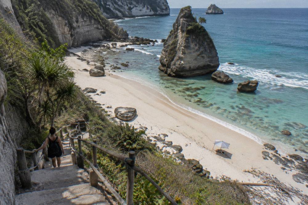 A white sand cove at the base of a limestone cliff with turquoise water