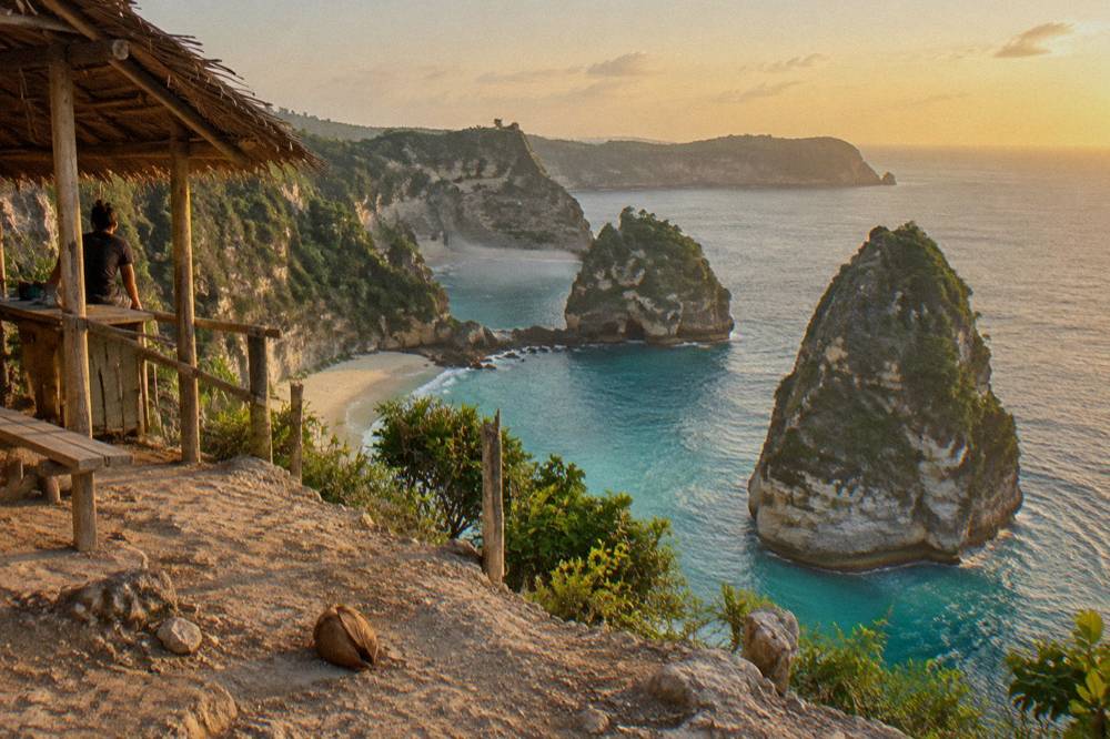 A wide sandy bay with offshore rock islets seen from a clifftop viewpoint