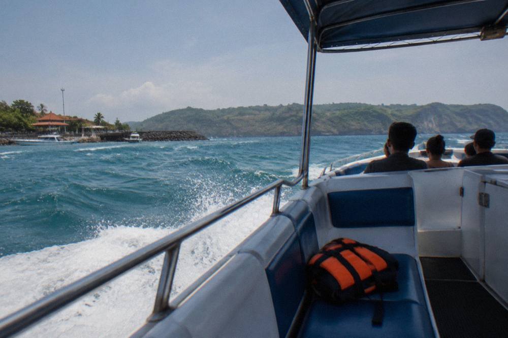 Fast boat underway on open water between Bali and a small island on the horizon