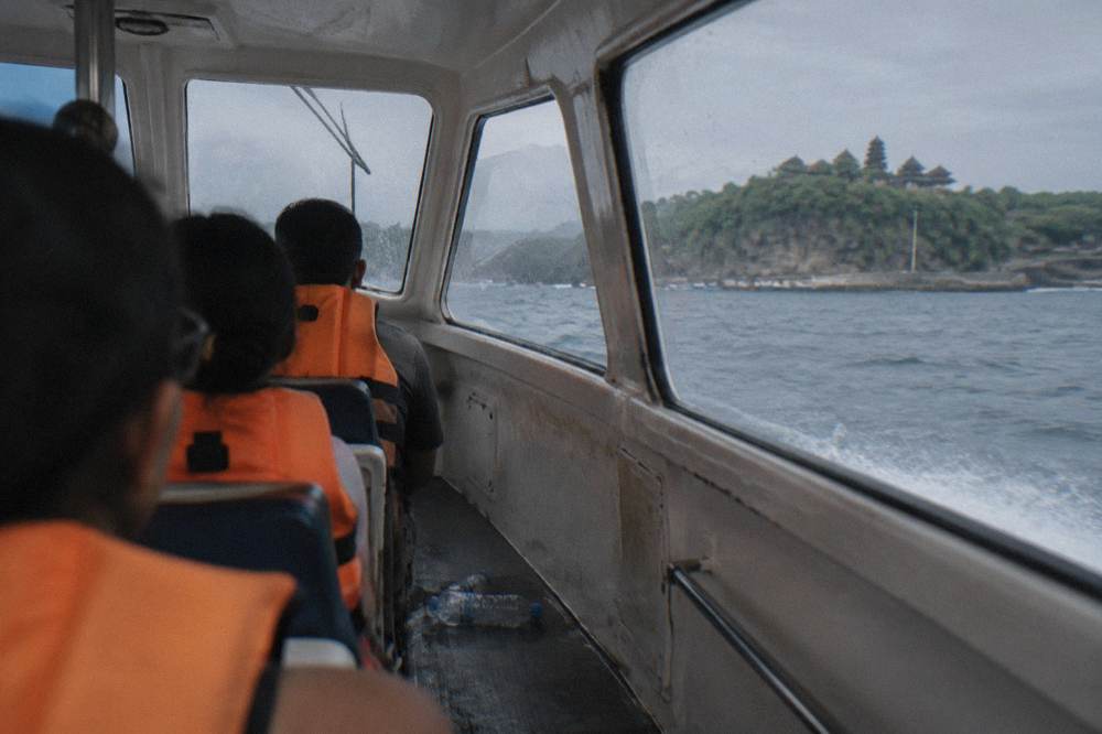 Passengers in life jackets seated inside a fast boat cabin during a crossing