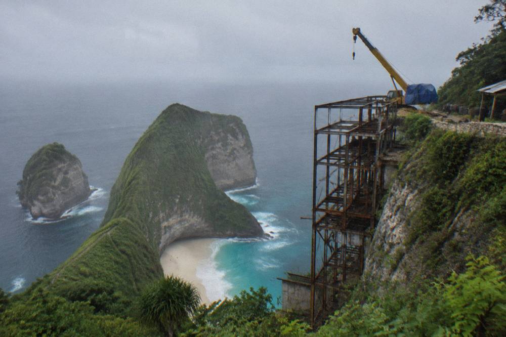 Unfinished metal lift structure and crane on the cliffside at Kelingking Beach