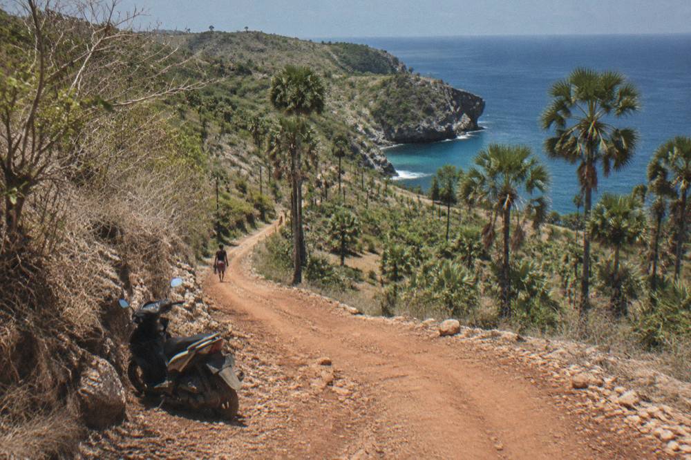 A winding coastal road on Nusa Penida with dry hills and blue sea beyond