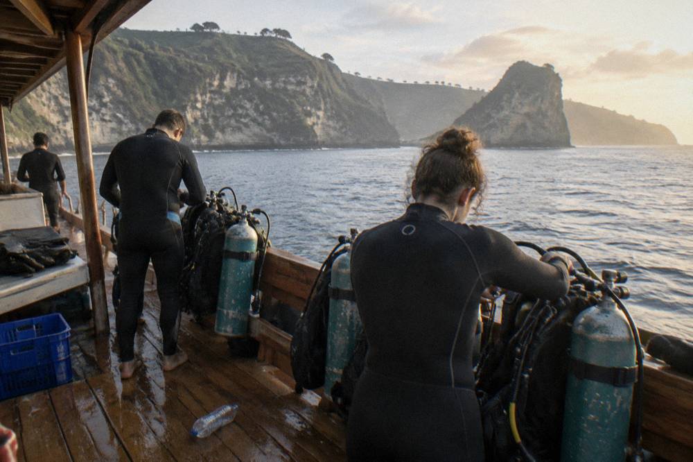 Scuba divers preparing equipment on a boat deck before a dive