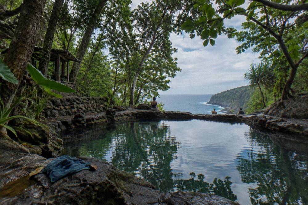 Freshwater natural pool surrounded by rocks and forest greenery near the sea