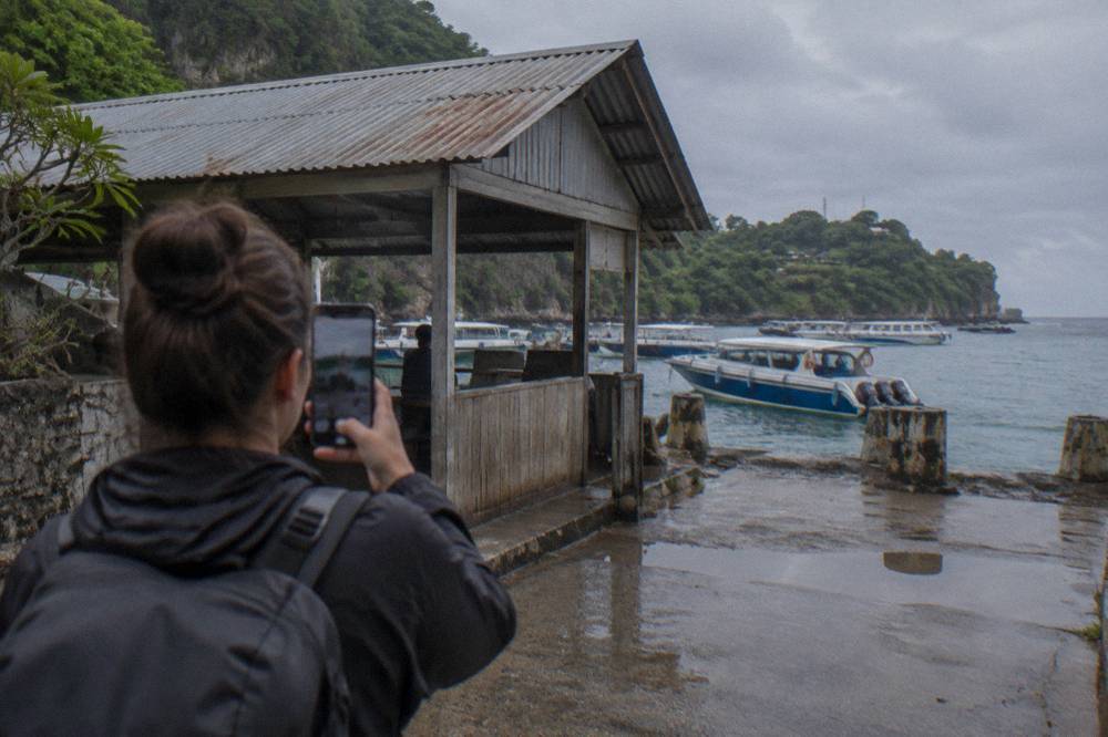 A traveller holding a phone showing a QR code at a harbour checkpoint