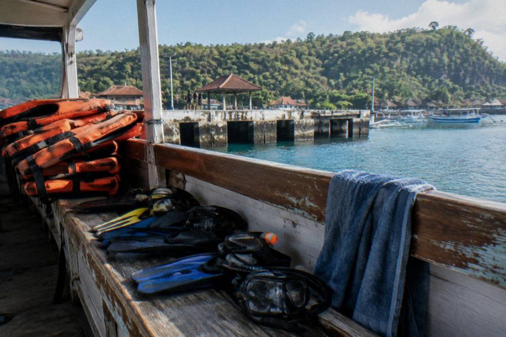 Snorkeling gear laid out on a boat bench with orange life jackets stacked beside it