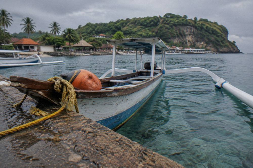 A wooden outrigger snorkeling boat moored over clear water near Nusa Penida