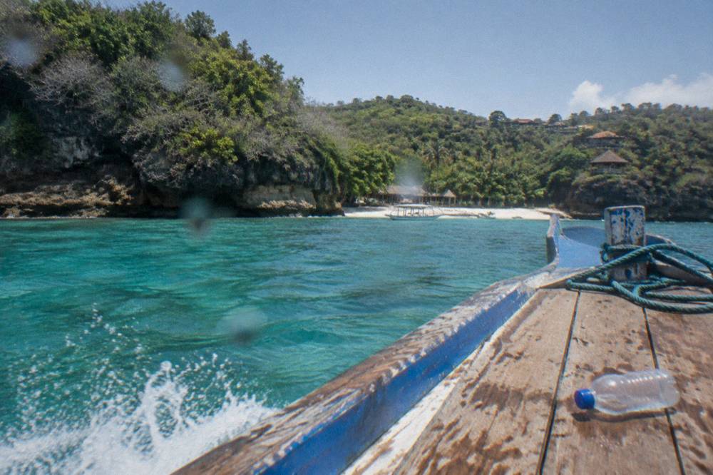 A small boat crossing clear shallow water between Nusa Penida and Nusa Lembongan