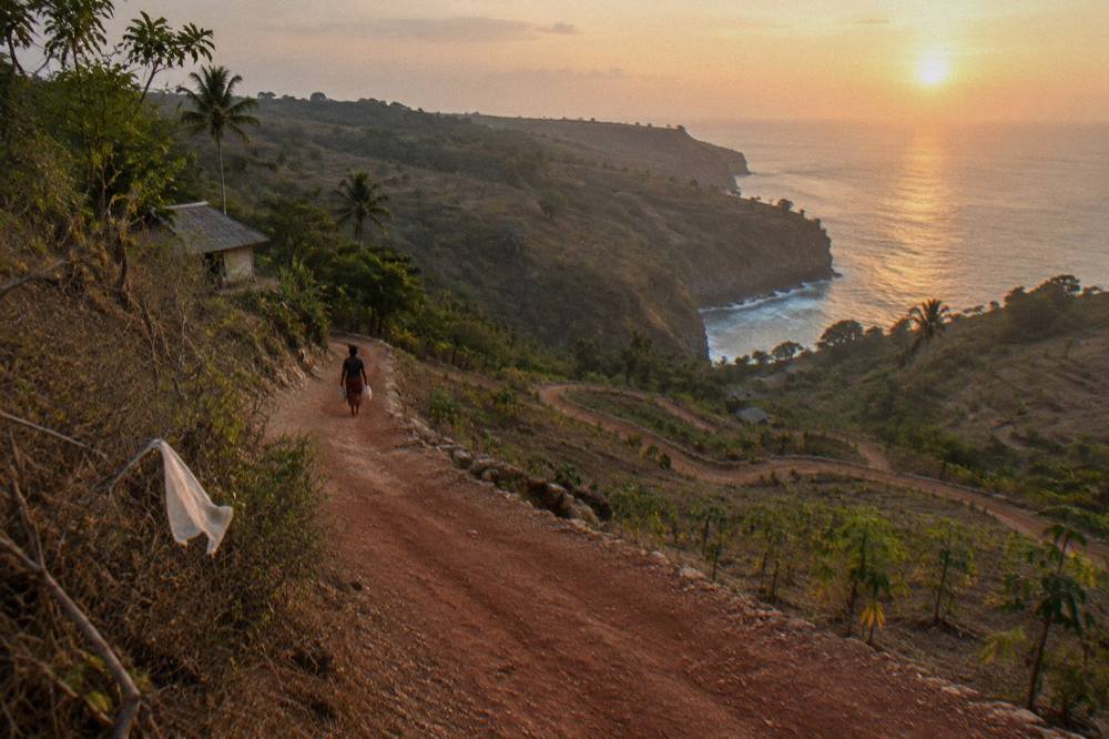 A coastal road winding along dry hills above the sea on Nusa Penida