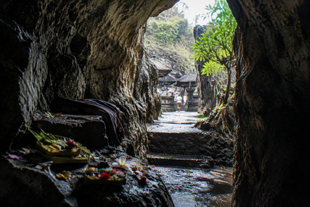 A cave temple entrance framed by rock and offerings on Nusa Penida