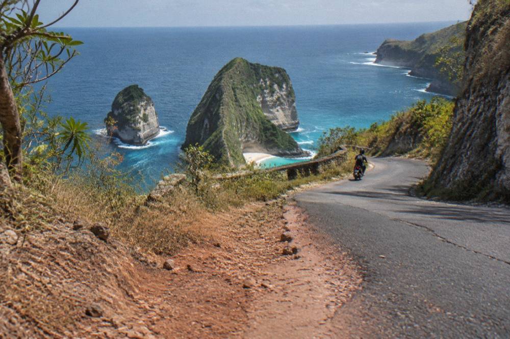 A coastal road on Nusa Penida winding above the sea toward the southwest cliffs