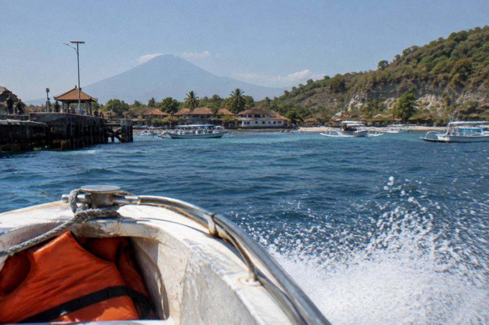 A fast boat cutting through open water with spray over the bow under a bright sky