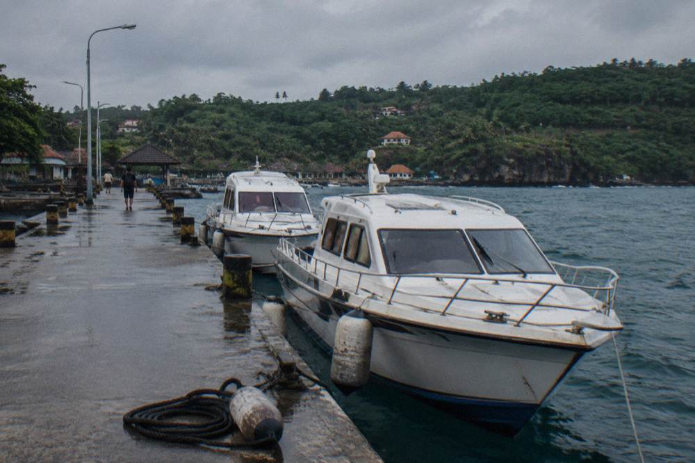 Fast boats moored at a wooden jetty in Nusa Penida harbour in late afternoon light